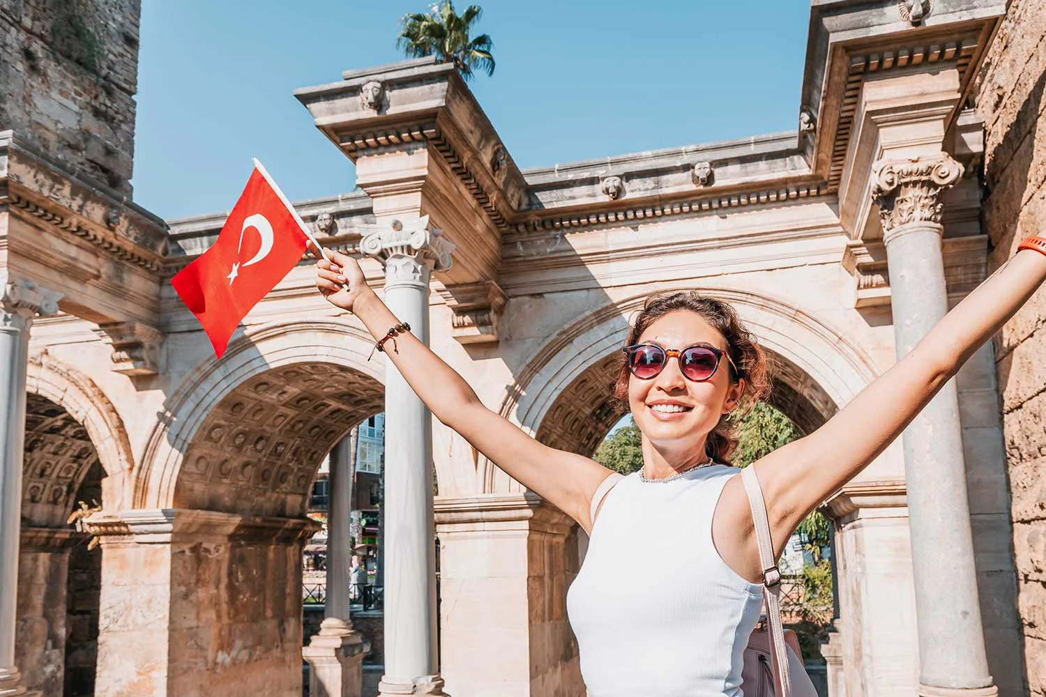 Reisende mit türkischer Flagge vor dem antiken Hadrianstor in Antalya